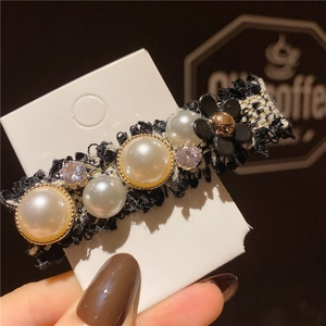 Détail d'une pince à cheveux en tweed avec fleurs, perles et strass sur carte