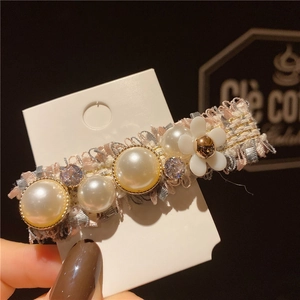 Détail d'une barrette en tweed avec perles blanches, fleur et cristaux scintillants