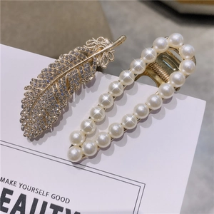Détail d'une pince à cheveux plume dorée avec cristaux et barrette en perles chic