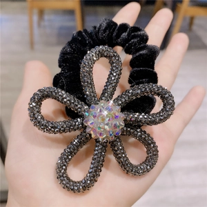 Detail of velvet hair ring with sparkling crystal flower and colorful rhinestone center