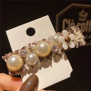 Détail de la pince à cheveux en tweed avec perles, fleur blanche et strass brillants