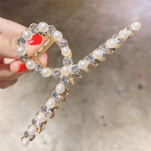 Détail d'une pince à cheveux dorée ornée de perles élégantes et de strass étincelants