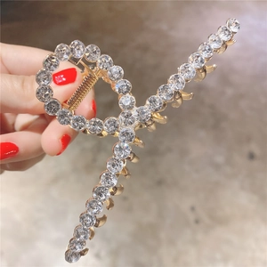 Détail d'une pince à cheveux en alliage doré avec strass brillants au design croisé