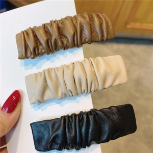 Drei plissierte Leder-Haarspangen in Braun, Beige und Schwarz auf einer Displaykarte