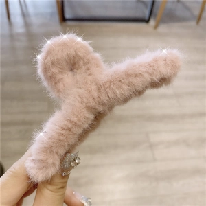 Close-up of soft plush faux fur hair claw clip in a gentle pink color for women