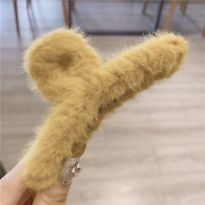 Close-up of soft mustard yellow plush faux fur hair claw clip held by hand
