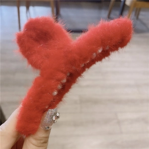 Close-up of a large red plush hair claw clip with soft faux fur and sturdy plastic teeth