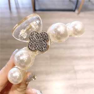 Vue détaillée de la pince à cheveux camélia avec perles et décor de trèfle en cristal