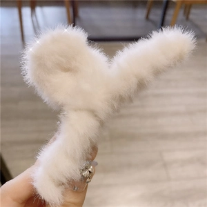 Close-up of a large white plush heart-shaped hair claw clip held in hand for women