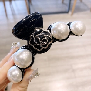 Vue détaillée d'une grande pince à cheveux noire avec des perles et un emblème de rose