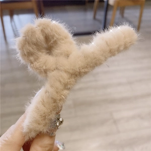 Detail view of the beige faux fur hair claw clip with soft texture and cross design
