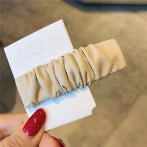 Detailaufnahme der beigefarbenen Haarspange aus plissiertem Leder mit Struktur