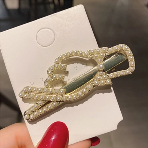 Détail de la pince à cheveux dorée avec nœud en perles élégantes et accents de cristal