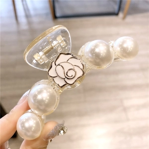 Détail d'une pince à cheveux élégante avec rose blanche et perles sur acrylique