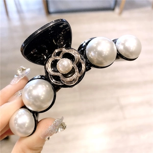 Détail de la pince à cheveux camélia avec perles blanches et fleur à bord doré
