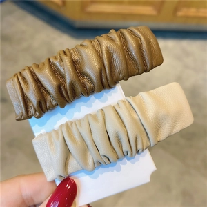 Zweiteiliges Set aus gefalteten Leder-Haarspangen in Dunkelbraun und Beige auf Karte