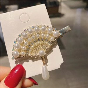Close-up of fan-shaped hair clip with pearls, rhinestones and a gold alloy finish