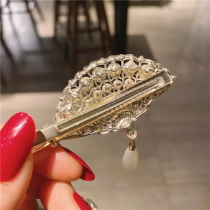 Detail of fan-shaped hair clip with pearls and drop pendant on gold镂空 base