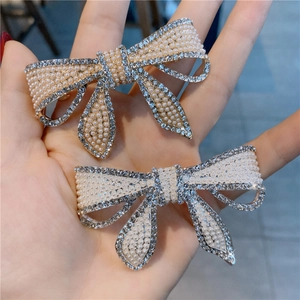 Détail de pinces à cheveux en forme de nœud avec strass et perles de nacre crème