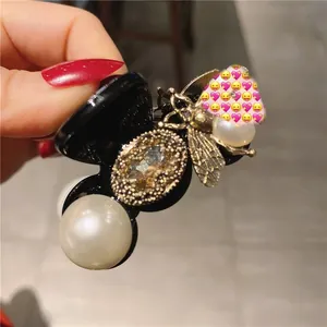 Detail van vintage gouden bijen haarklem met groot kristal en witte parelversiering