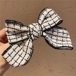 Detailed macro view of black and white tweed bow hair clip with woven texture