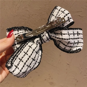 Close-up of black and white checkered tweed bow hair clip with silver metal spring clip