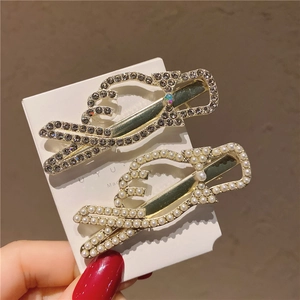 Détail de barrettes dorées avec des perles blanches incrustées et des strass étincelants