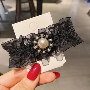 Close-up of vintage black lace hair clip featuring a large central faux pearl and rhinestones