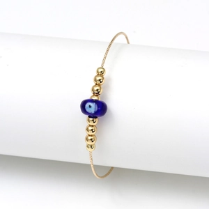 Minimalist golden chain bracelet with blue evil eye bead and polished gold beads