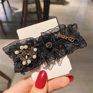 Close-up of black lace hair clip with pearl accents and square gray crystal detail