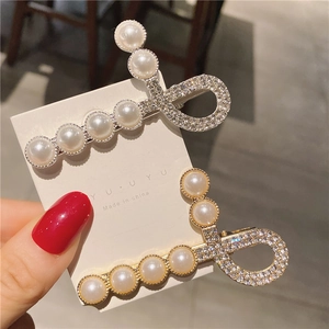 Détail de barrettes élégantes avec perles blanches polies et cristaux de strass brillants