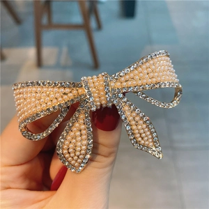 Détails d'une barrette noeud ornée de perles crème et de strass brillants en gros plan