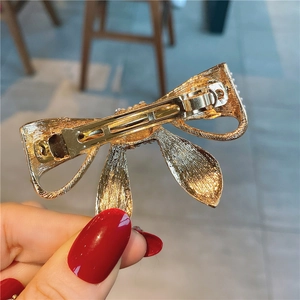Détail du fermoir à ressort en métal doré de la barrette nœud pour un maintien sûr