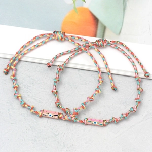 Detail view of woven evil eye bracelets with pink enamel charms and adjustable cords