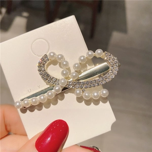 Détail d'une barrette élégante ornée de perles blanches et de strass sur son support