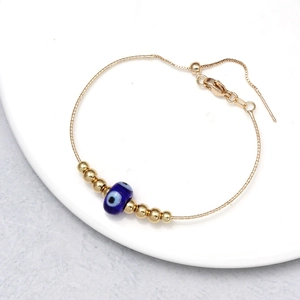 Close-up of golden evil eye bracelet with blue beads and adjustable lobster clasp