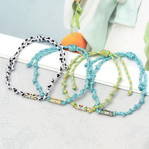 Detail of four handmade braided Evil Eye bracelets with golden metal charms and color cords