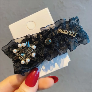 Macro shot of black layered lace hair clip with pearls, rhinestones and Loveme gold charm
