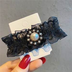Detailed macro of vintage black lace hair clip with pearl centerpiece and embroidery
