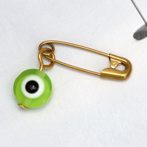 Detalle de broche de imperdible dorado de ojo turco con colgante de cuenta verde claro