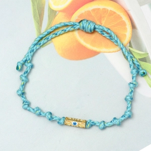 Detail of hand-woven sky blue cord bracelet with gold Evil Eye charm and knots