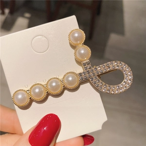 Détail de la pince à cheveux dorée ornée de perles élégantes et strass scintillants