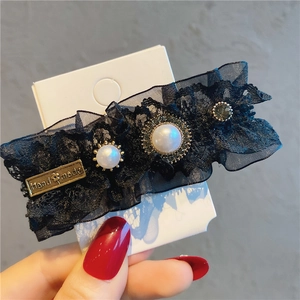 Close-up of black lace hair clip with pearls, rhinestones and Handmade metal tag