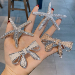 Détails de barrettes à cheveux étoile de mer en strass et nœud en perles dans la main