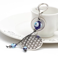 Detailed view of Evil Eye keychain with blue glass beads and Flower of Life metal pendant