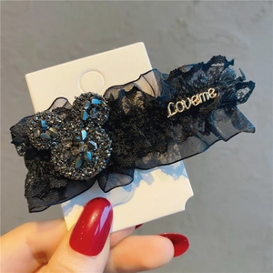 Close-up of black lace hair clip with rhinestone mouse icon and gold Loveme tag