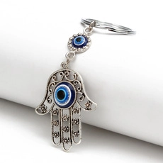 Macro detail of the silver alloy Hamsa Hand keychain with intricate hollow carvings and Evil Eye beads
