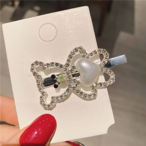 Détail d'une pince à cheveux ourson en strass brillants avec un cœur en perle