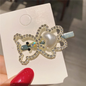 Détail d'une pince à cheveux papillon avec strass et une perle blanche en cœur