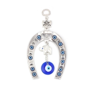 Macro shot of silver horseshoe wall hanging with blue evil eye bead and elephant charm